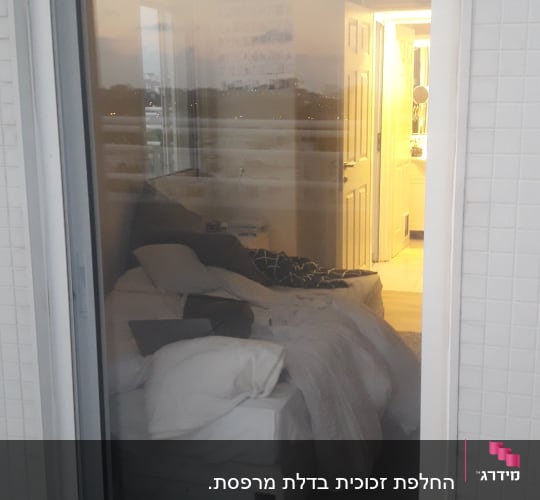 דלת זכוכית עם השתקפות חדר שינה מואר